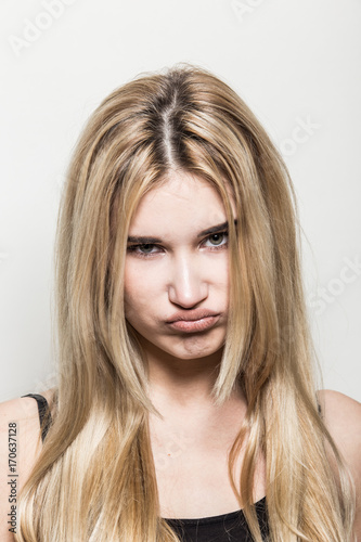 Close-up portrait of a young beautiful blonde girl on a light background. A woman with different emotions on her face.