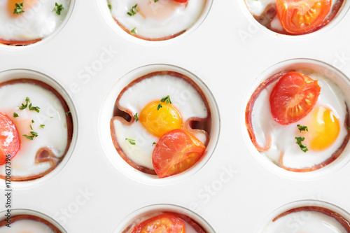 Muffin tin with tasty eggs, tomatoes and ham, closeup