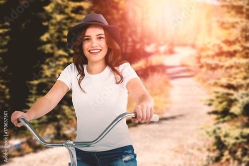 Composite image of portrait of happy woman cycling on bicycle