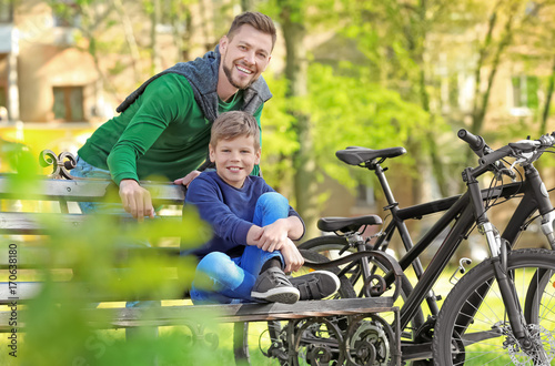 Dad and son sitting with their bicycles outdoors © Africa Studio