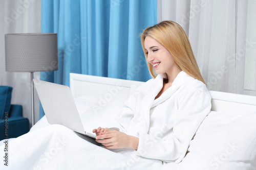 Young woman using laptop in hotel room