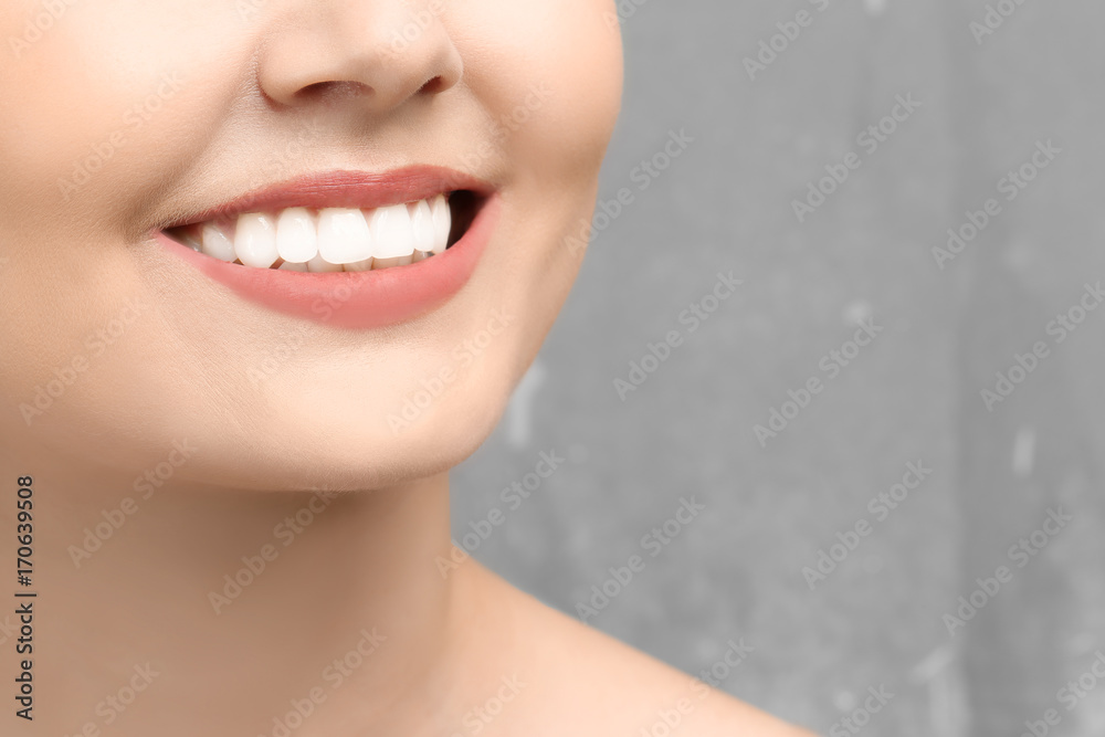 Naklejka premium Young woman with healthy teeth on grey background, closeup