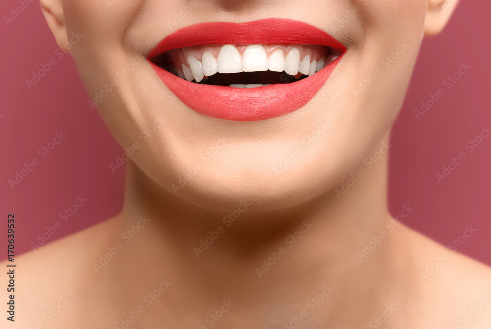 Fototapeta premium Young woman with healthy teeth laughing on colour background, closeup