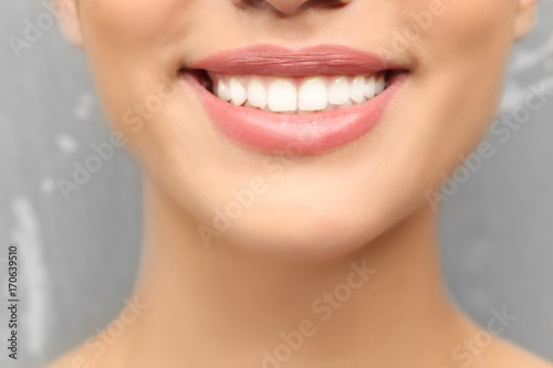 Young woman with healthy teeth on grey background  closeup