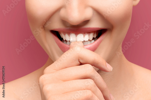Young laughing woman biting her finger on colour background, closeup