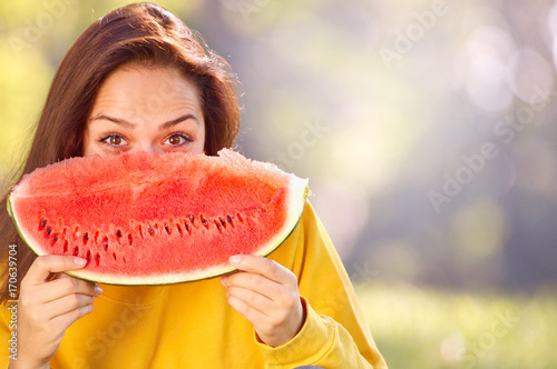 Happy young woman eating watermelon in the park