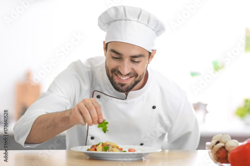 Young male chef garnishing his dish in kitchen