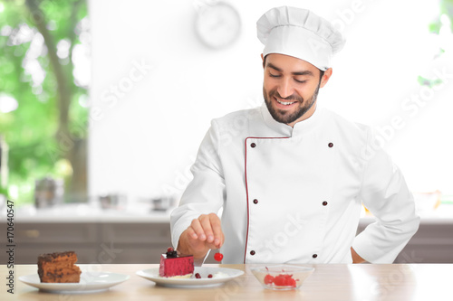 Young male chef decorating cake in kitchen