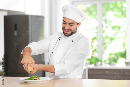 Young male chef adding spic...