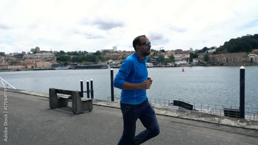 Young man jogging in city near river, super slow motion 120fps
