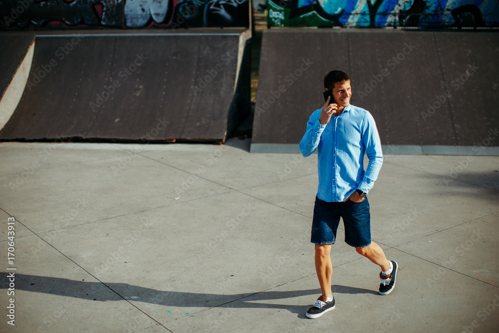 Young modern man talking on the phone in the skate park