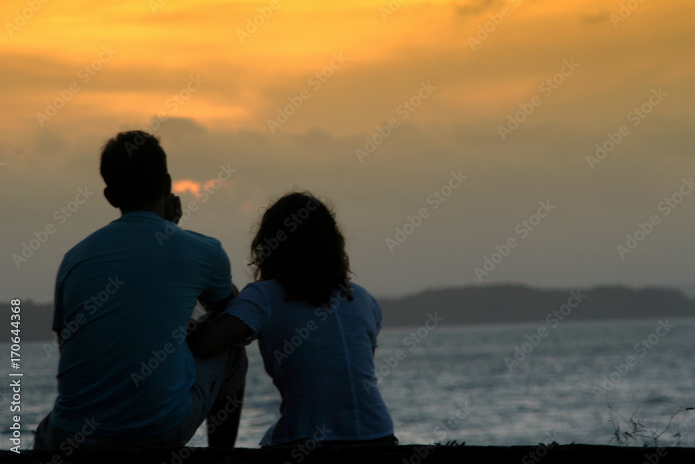 Romantic couple on the beach in Brazil at colorful sunset on background