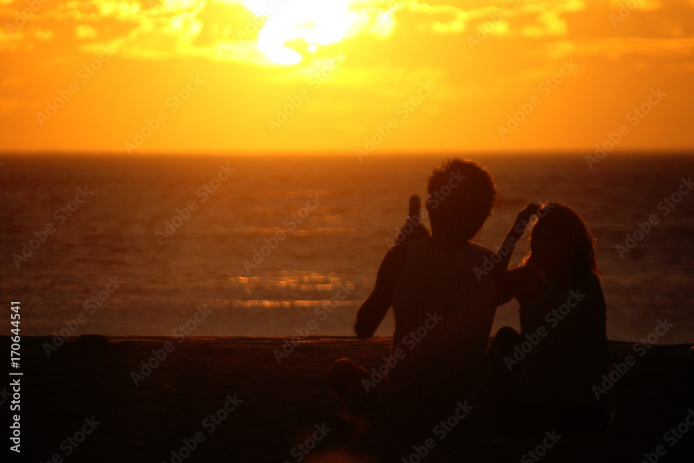Romantic couple on the beach in Brazil at colorful sunset on background