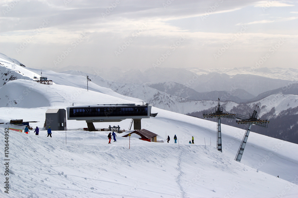 Fototapeta premium Skiers and snowboarders riding on a ski slope in Sochi mountain resort snowy winter
