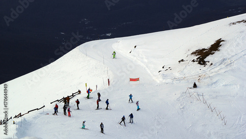 Skiers and snowboarders riding on a ski slope in Sochi mountain resort snowy winter photo