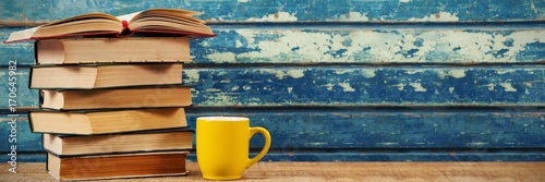 Stack of books with cup on table