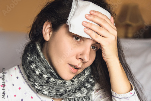 Sick woman caught cold and fever or headache bed at home. Apply the dressing wet to the head