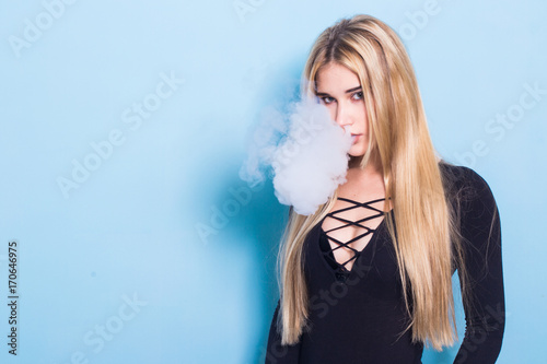 Close-up Portrait of sexy young hipster smoking (vaping) girl. Vapor concept. Vaping e-Cigarette.