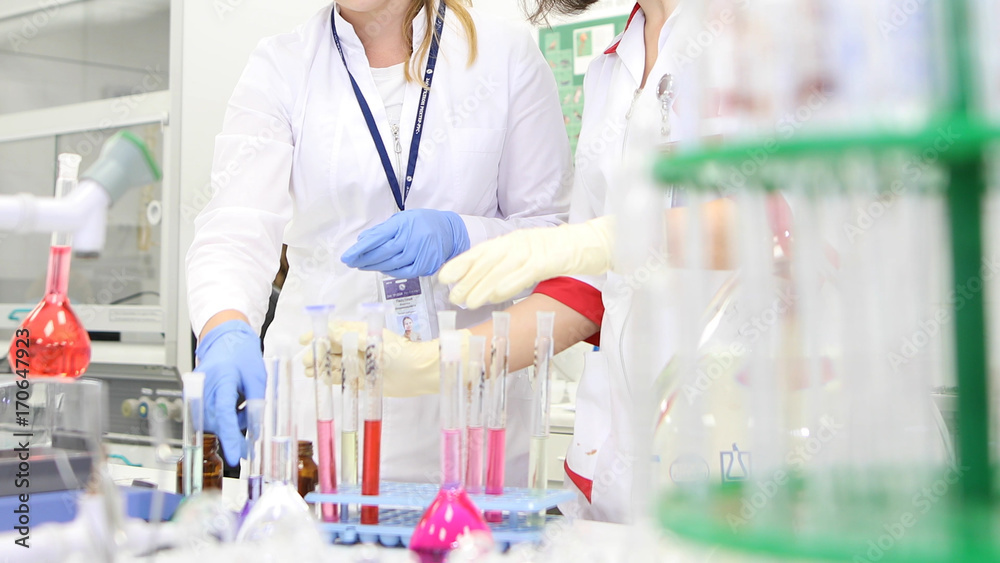 Foto de Two female scientist working in laboratory with flasks wearing ...
