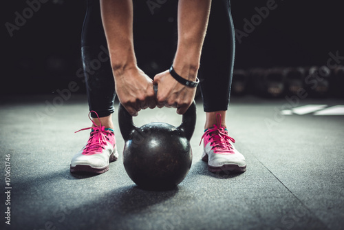 Woman in gym holding a kettlebell. Working Out at Crossfit.