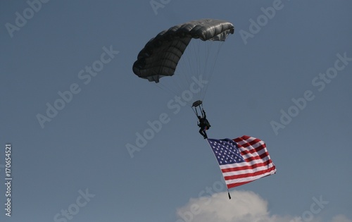 Sky diver carrying american flag with parachute.