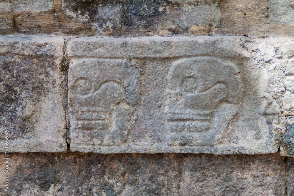 Carved skulls at the Platform of Sculls at the archeological site Chichen Itza, Mexico