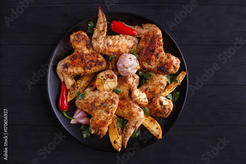 Grilled chicken wings with lemon and garlic on black plate. Cooking concept, meat dishes, homemade food