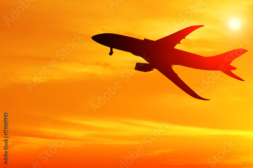 Silhouette of airplane taking off flight with orange sky background