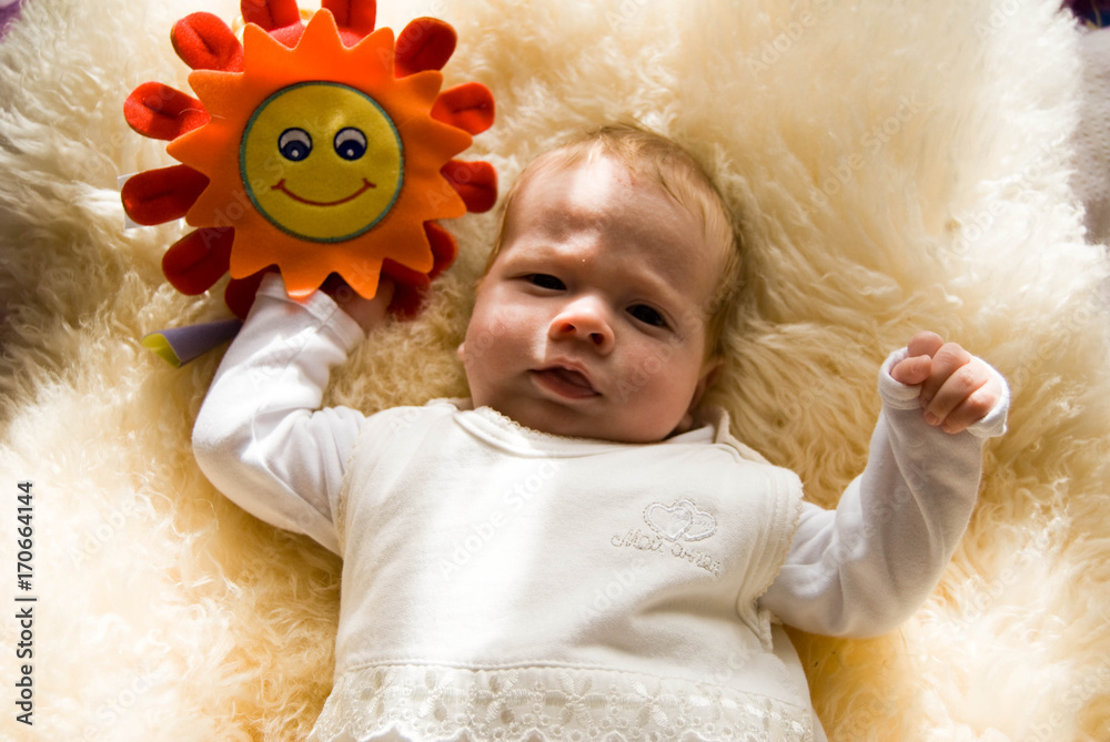 newborn happy sweet baby on furry blanket with toy sun in soft colors