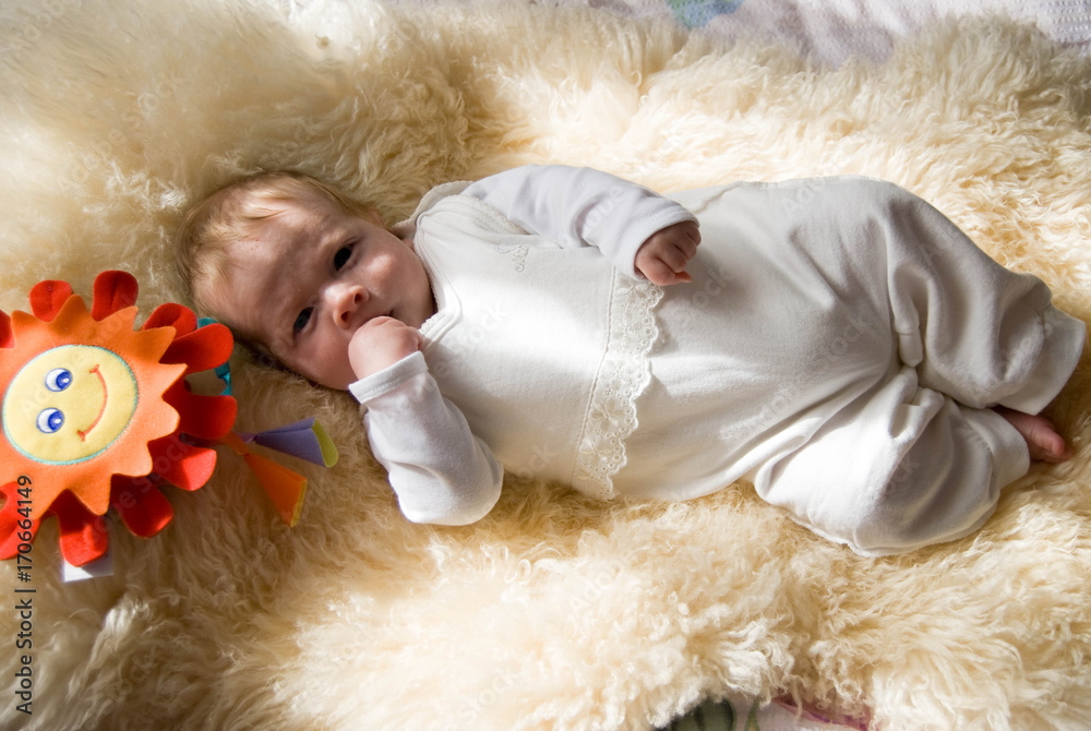 newborn happy sweet baby on furry blanket with toy sun in soft colors