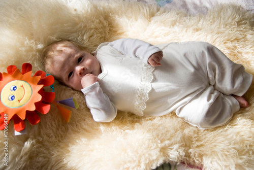 Obraz na płótnie newborn happy sweet baby on furry blanket with toy sun in soft colors w salonie