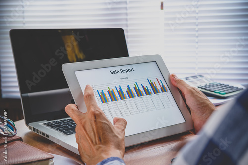 Close-up of a tablet computer with financial data on screen in hands of businessman and working.