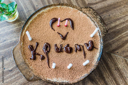 Flat top view of homemade tiramisu cake with birthday candles, heart and chocolate icing photo