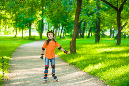 Girl learn to roller skate in summer park. Space for text.