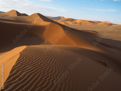 Natural curved ridge line and wind blow pattern of rusty red sand dune with shade and shadow on vast desert landscape horizon background  Sossus  Namib desert