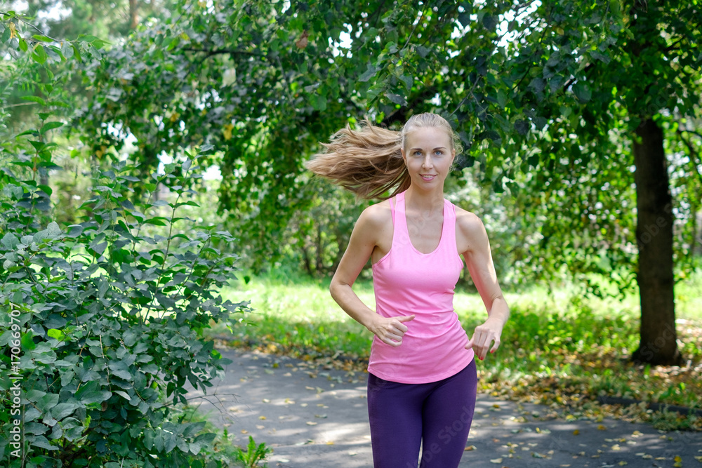 Beautiful young woman running in green park on sunny summer day Beautiful young woman running in green park on sunny summer day