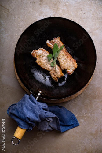 Two pork loin chops cooking in a wok with sage. photo