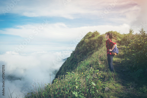 Fototapeta Naklejka Na Ścianę i Meble -  successful woman backpacker hiking on sunrise mountain peak cliff