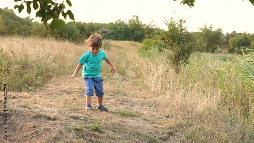 Adorable boy in a t-shirt and shorts playing on the shore of the lake throwing stones into the water, slow motion. Adorable boy in a t-shirt and shorts playing on the shore of the lake throwing stones into the water, slow motion.