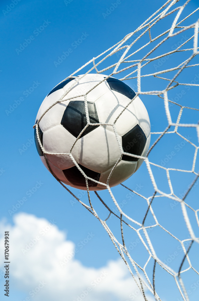Soccer football in Goal net with the sky field.