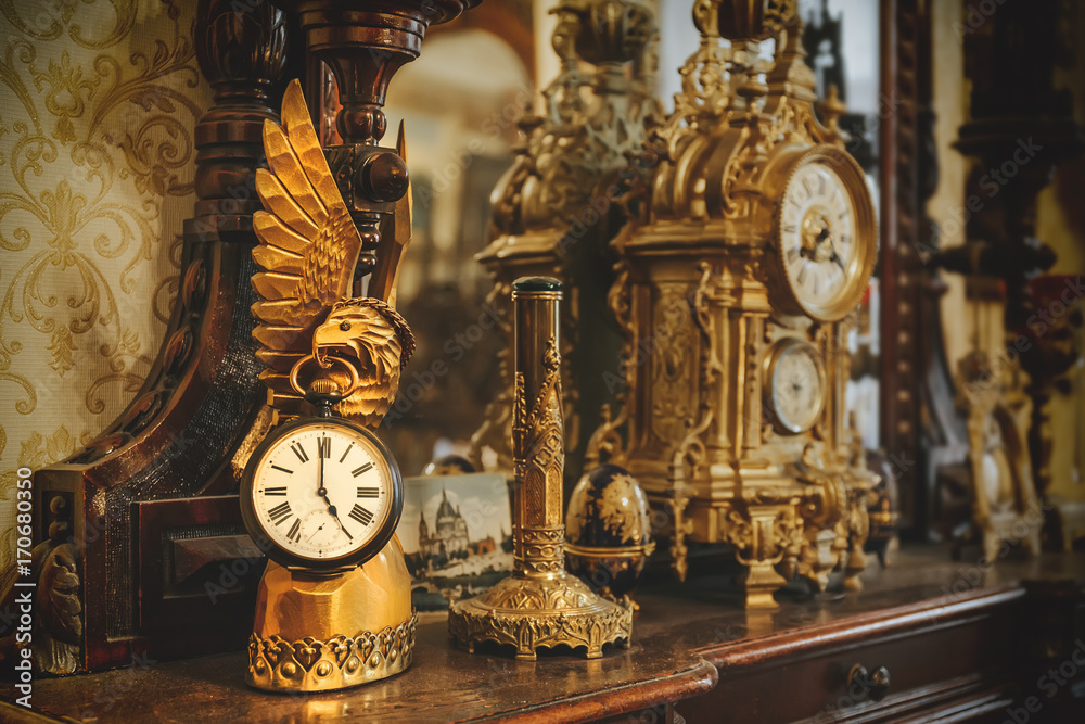Old vintage antique bronze clock and utensil on wooden shelf