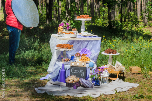  the organization of the Banquet . the process of shooting food. woman holding photo reflector . On the table, dishes in the style of Provence and a variety of sweets