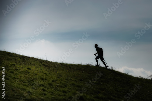Nordic walking uphill on a hilly meadow in silhouette