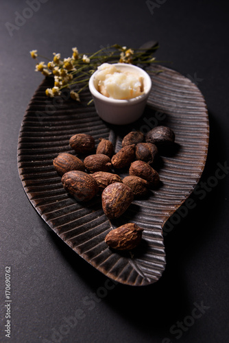 Shea butter and shea butter nuts on black background photo