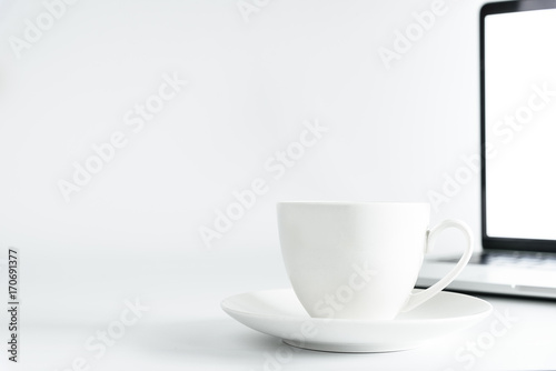 Coffee Cup and computer desktop on white office desk table with a silver pen and note for working in the morning with closeup view and copy space conecpt.