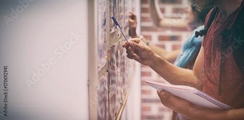Obraz na plátně Casual students searching something on notice board
