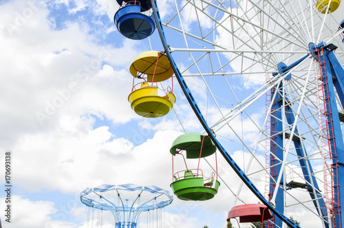 Bright Ferris Wheel on blue sky background in amusement park at sunny day. Concept for entertainment.