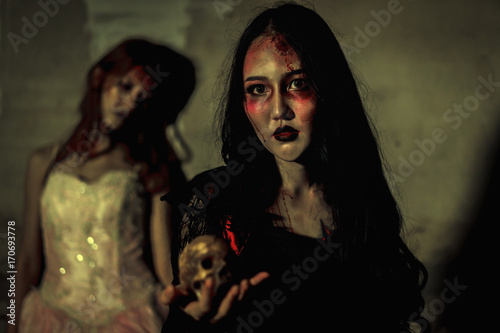 Witch death the ghost holding skull and zombie in dress women with blood skin is screaming darkness and nightmare background, horror of scary fear on hell is monster devil girl in halloween festival 