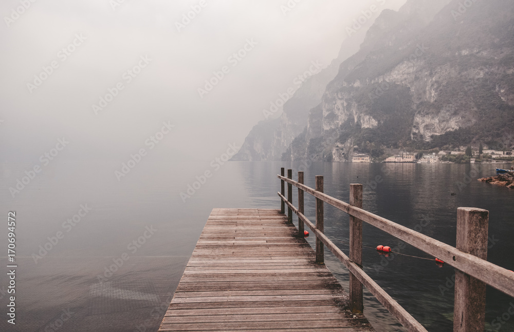 Wooden pier on the lake against the backdrop of the mountains, Garda, Italy