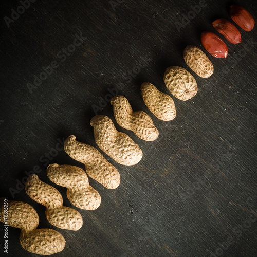 Fresh peanuts in peel and shell. Dark wooden background. Vegetarian food.